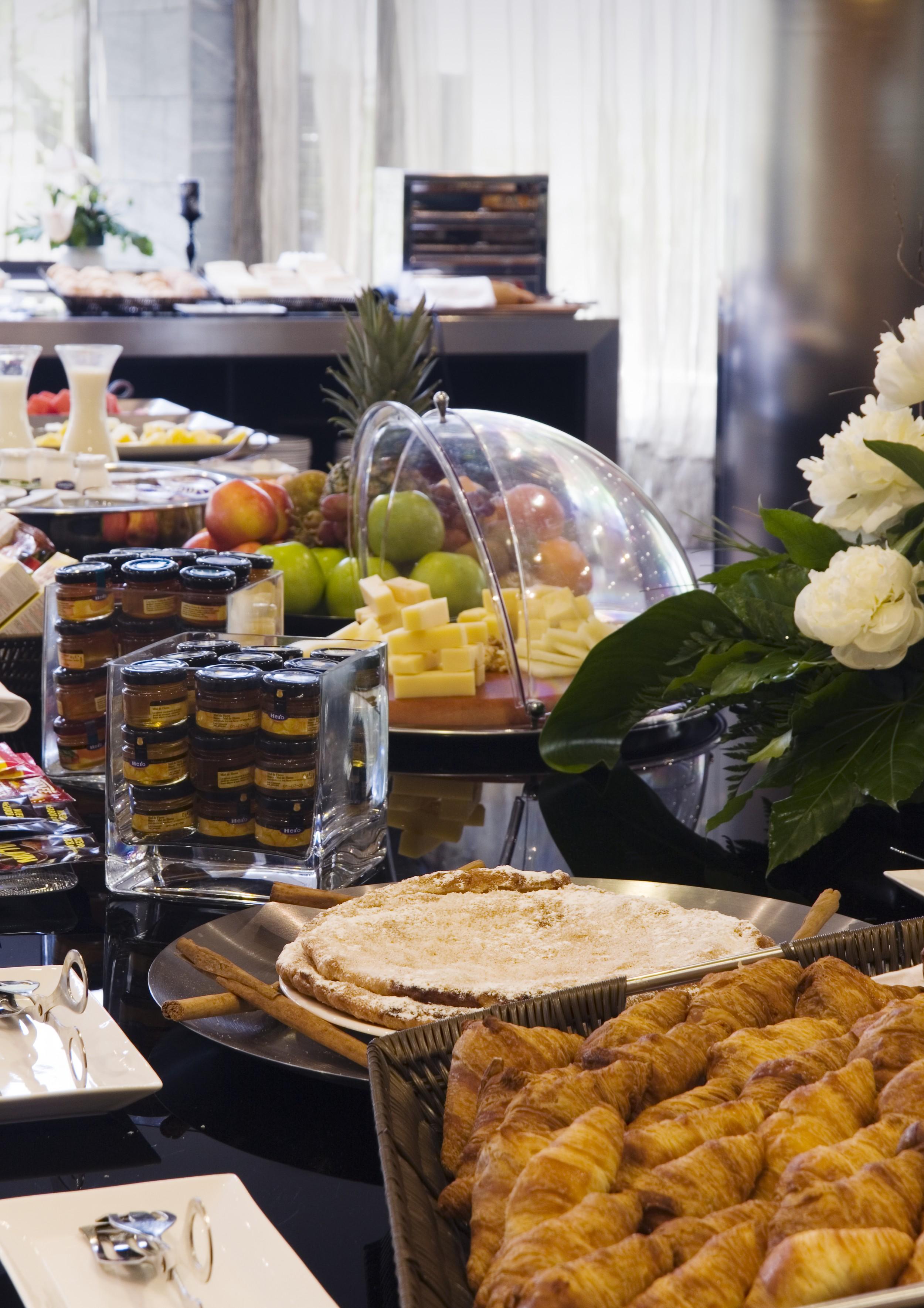فندق يوروستارز بالاس قرطبة المظهر الخارجي الصورة The photo shows a buffet-style arrangement with a variety of food items. There are fruits such as apples and grapes displayed prominently, along with a selection of cheeses presented on a wooden platter. A glass dome covers some of the items, possibl
