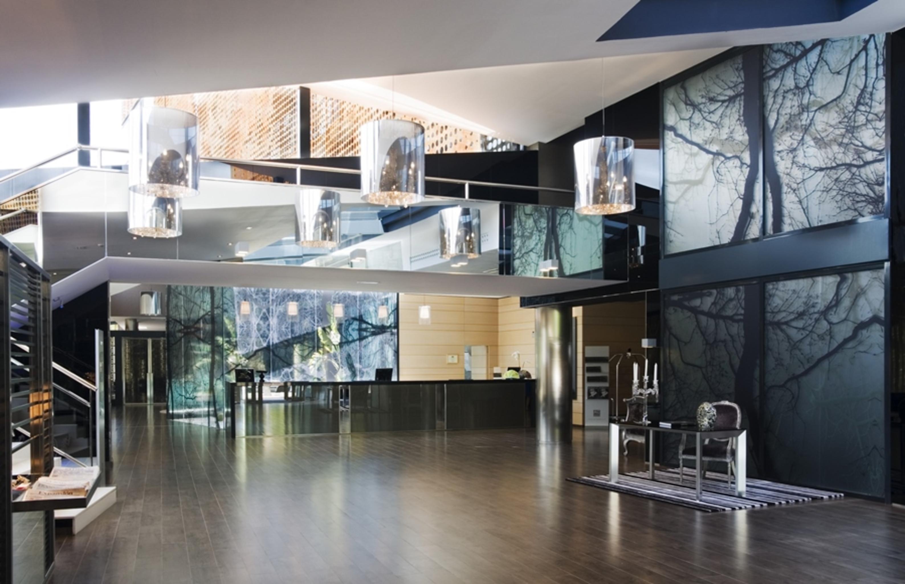 فندق يوروستارز بالاس قرطبة المظهر الداخلي الصورة The photo shows a modern interior space, likely an entrance or lobby area. The design features:

- A spacious layout with a polished wooden floor.
- Large glass panels that reflect light, creating an open and airy feel.
- Artistic wall décor that inc