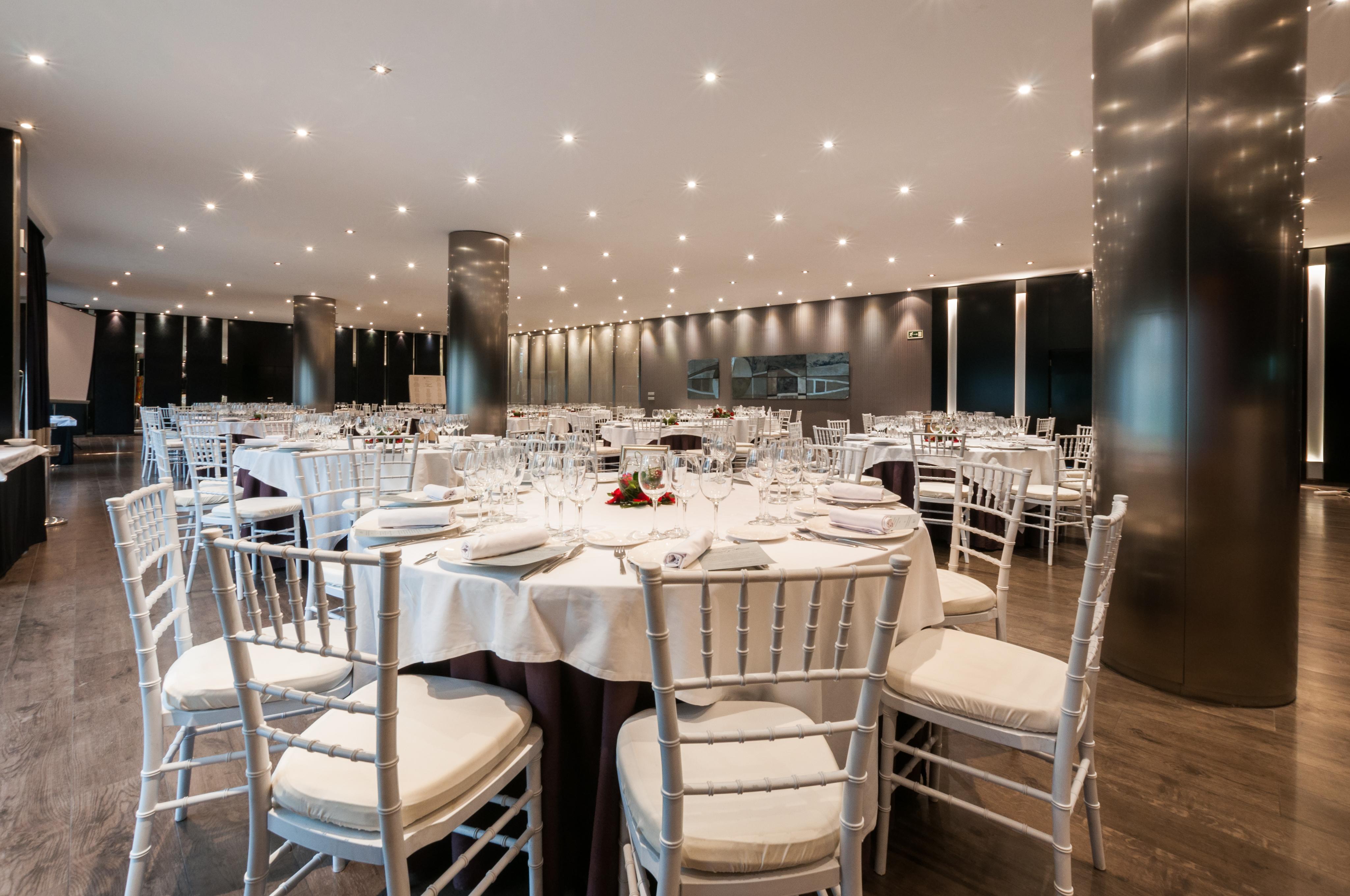 فندق يوروستارز بالاس قرطبة المظهر الخارجي الصورة The photo shows an elegant dining setting in a spacious restaurant. There are several round tables, each with white tablecloths and neatly arranged place settings, including glasses, plates, and utensils. The chairs are white with padded seats, provi