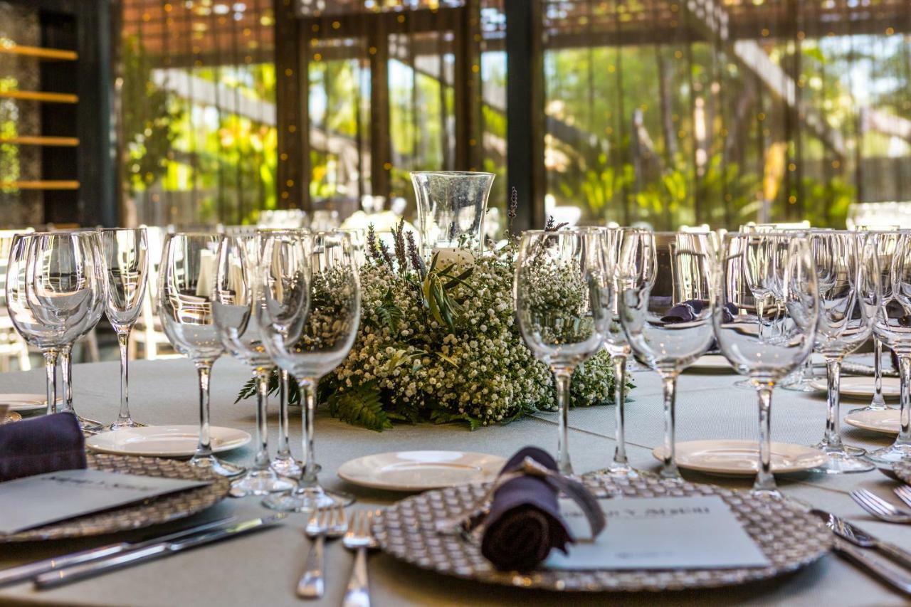 فندق يوروستارز بالاس قرطبة المظهر الخارجي الصورة The photo displays an elegantly set dining table arranged for a formal event. The table is adorned with a centerpiece made of white flowers and greenery, surrounded by numerous glassware, including wine glasses and water goblets. Each place setting i